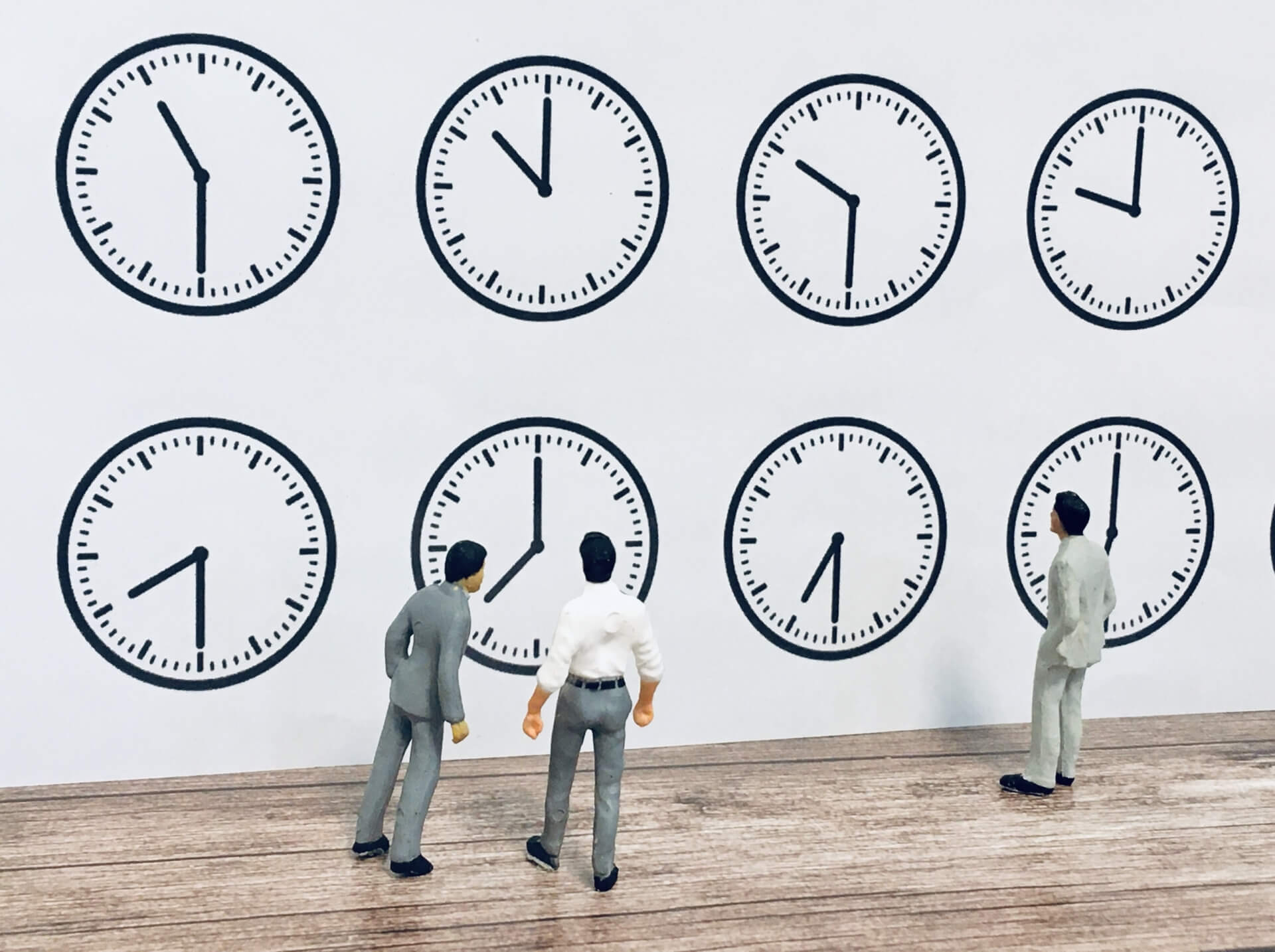 労働時間制度の違いのイメージ：複数の時計とビジネスパーソンのミニチュア